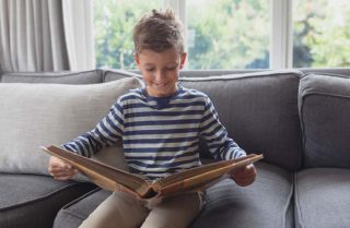Boy sitting on couch holding life book