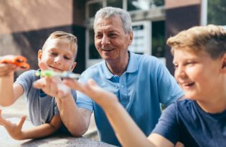 A man and two children play outside with toys