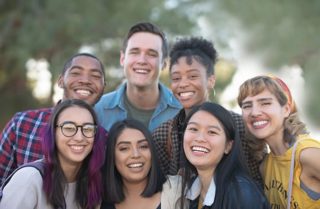 Diverse group of teens standing outside and smiling at the camera