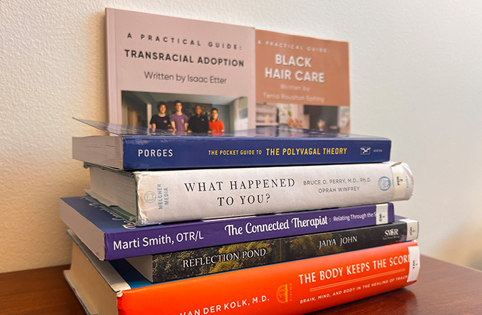 A stack of books with a variety of titles about adoption and foster care